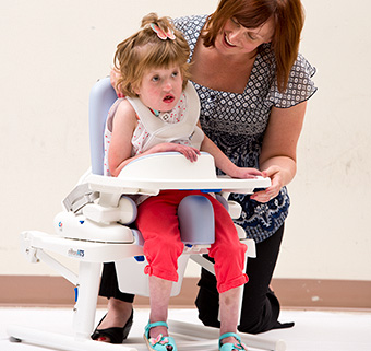 A girl using the Rifton HTS with the assistance of a caregiver