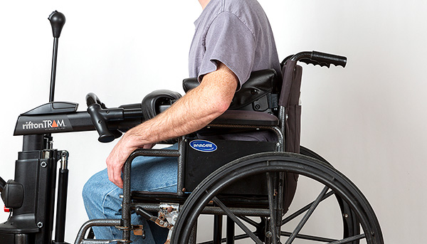 A man being transferred out of a wheelchair with a Rifton TRAM