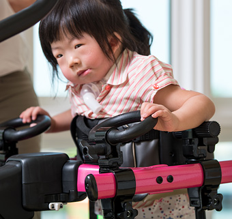 A little girl walking in a pink Rifton Pacer gait trainer on a treadmill