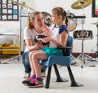 A child with autism sits in a Rifton Compass Chair to participate in music class.
