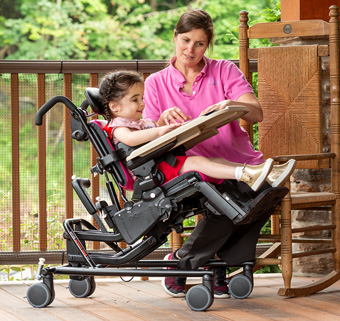 A girl sits on a Rifton Activity Chair and reads a story book with her caretaker.