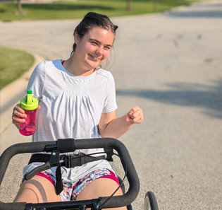 A young woman rides a tricycle and smiles.