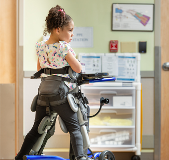A girl stands in a Rifton Stander in prone position