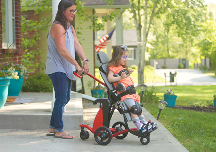 A girl stands in Rifton Stander while her mother adjusts the angle of the Stander.