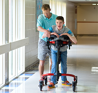a caretaker guiding a client in a red rifton dynamic pacer in a hallway
