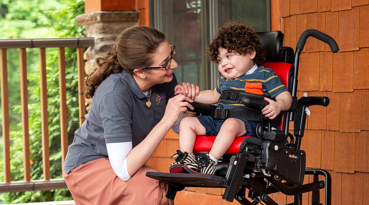 Boy in Rifton activity chair with therapist
