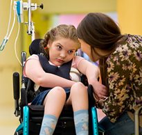 A Pediatric Life Care Planner positions a young girl with special needs in her adaptive equipment