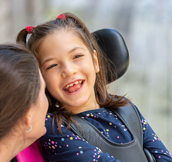 A little girl sitting in a Rifton Activity Chair, smiling