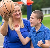A boy with disabilities playing basketball with his therapist