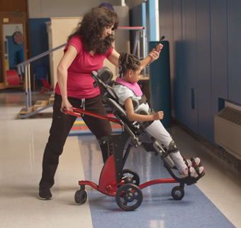 A physical therapists adjust the angle of Rifton supine stander with a young girl positioned in it.